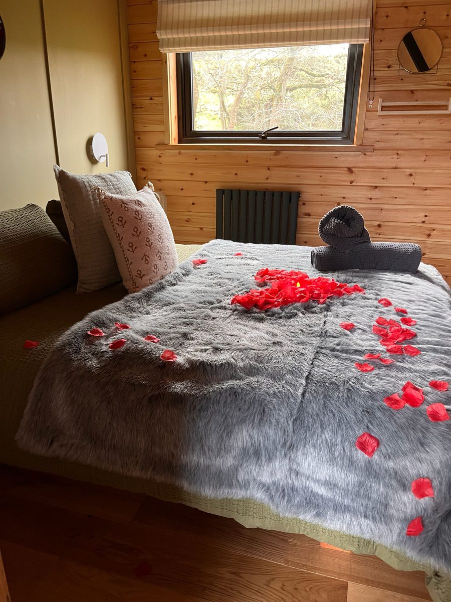 Holiday lodge bedroom dressed for arrival, with a faux-fur throw and folded towels on a made bed