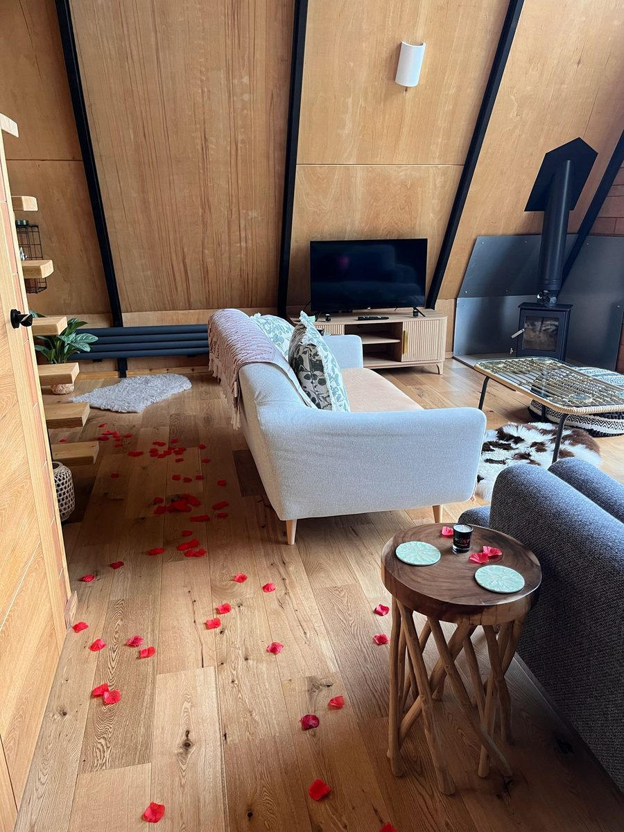 Lodge lounge cleaned and styled for guests, with a wood-burning stove and timber A-frame walls